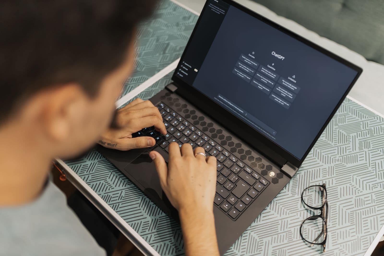 A person working at a laptop with an AI assistant chat interface open, reviewing generated output