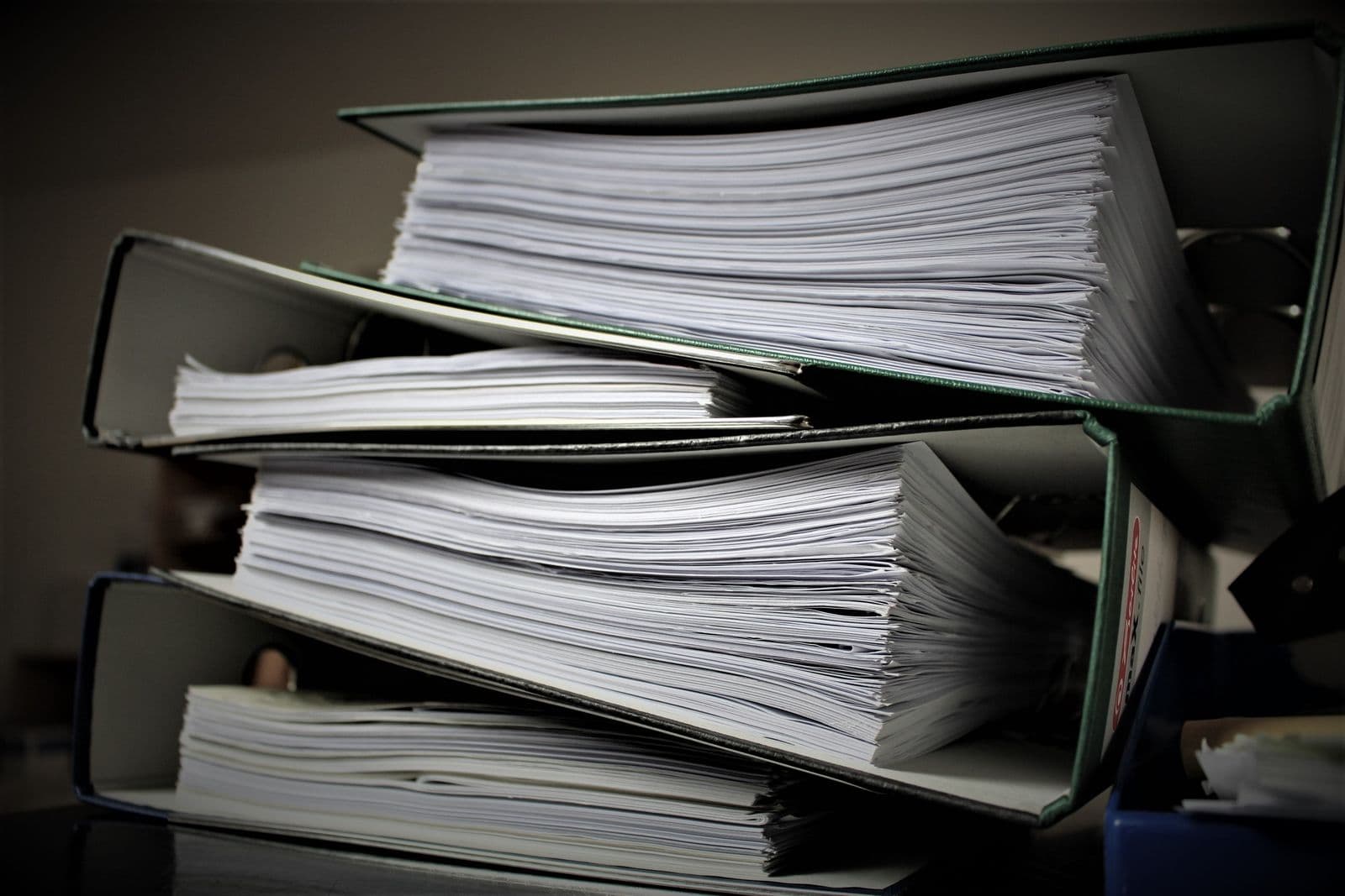 Stacks of paper documents and forms being scanned and digitized in an office