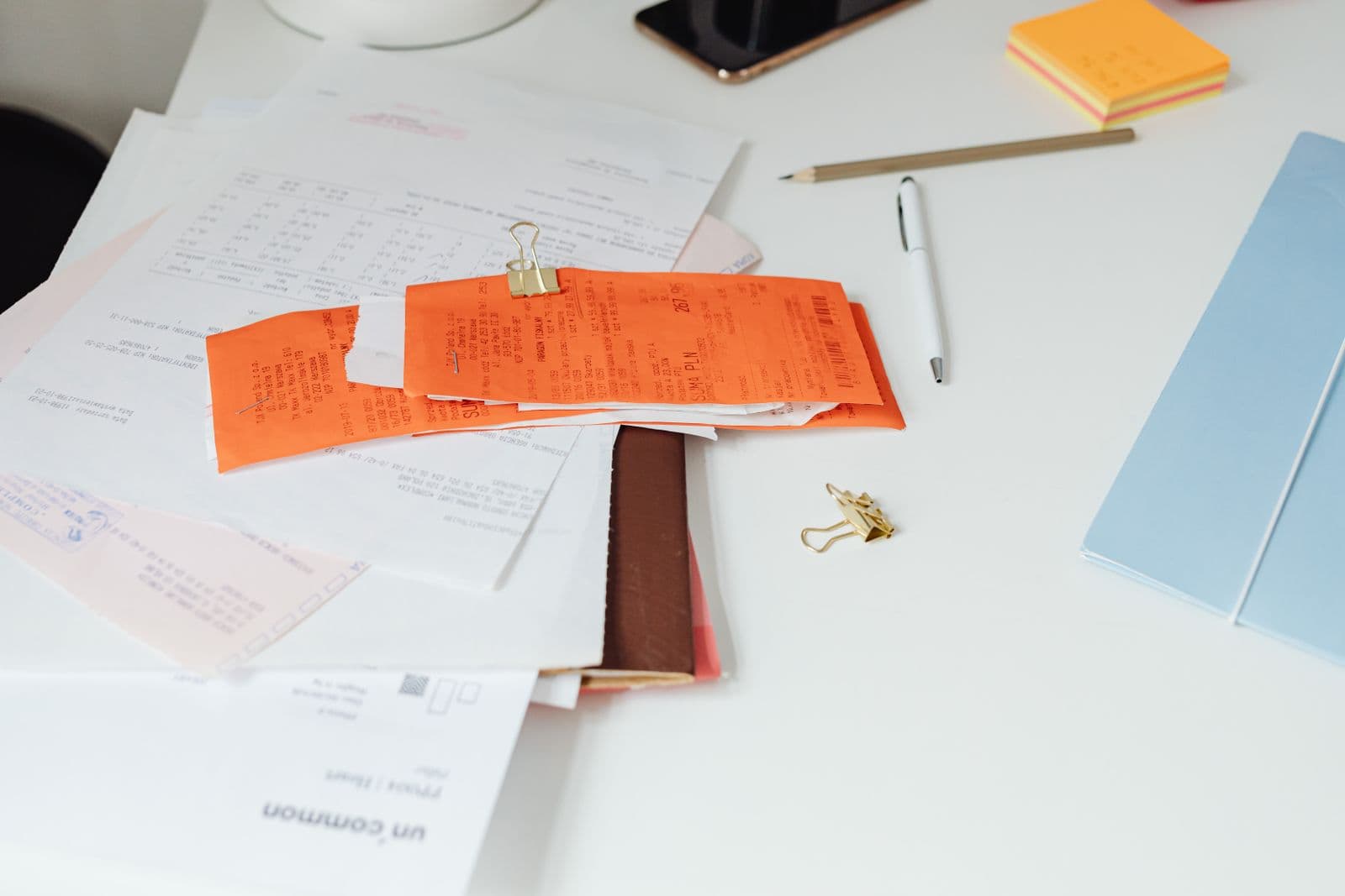 An accounts payable desk with invoices, a calculator and a laptop showing a payment dashboard