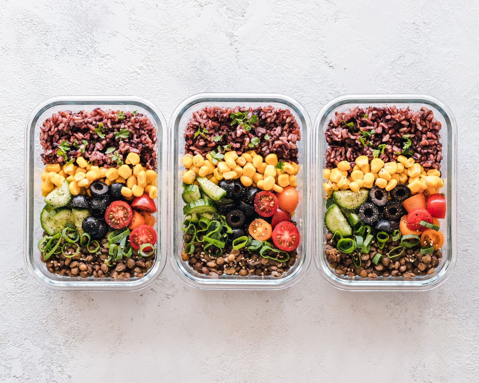 Prepared meals in containers arranged with fresh ingredients