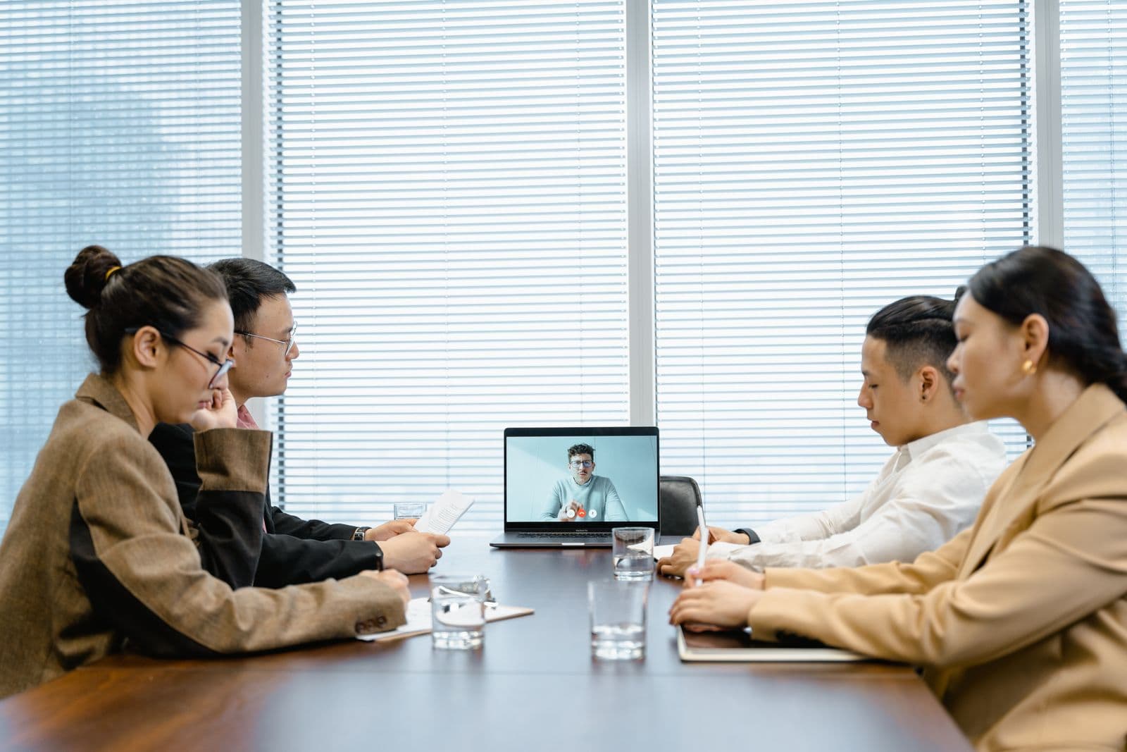 A video conference call in progress with participants on laptops while an AI meeting assistant captures notes