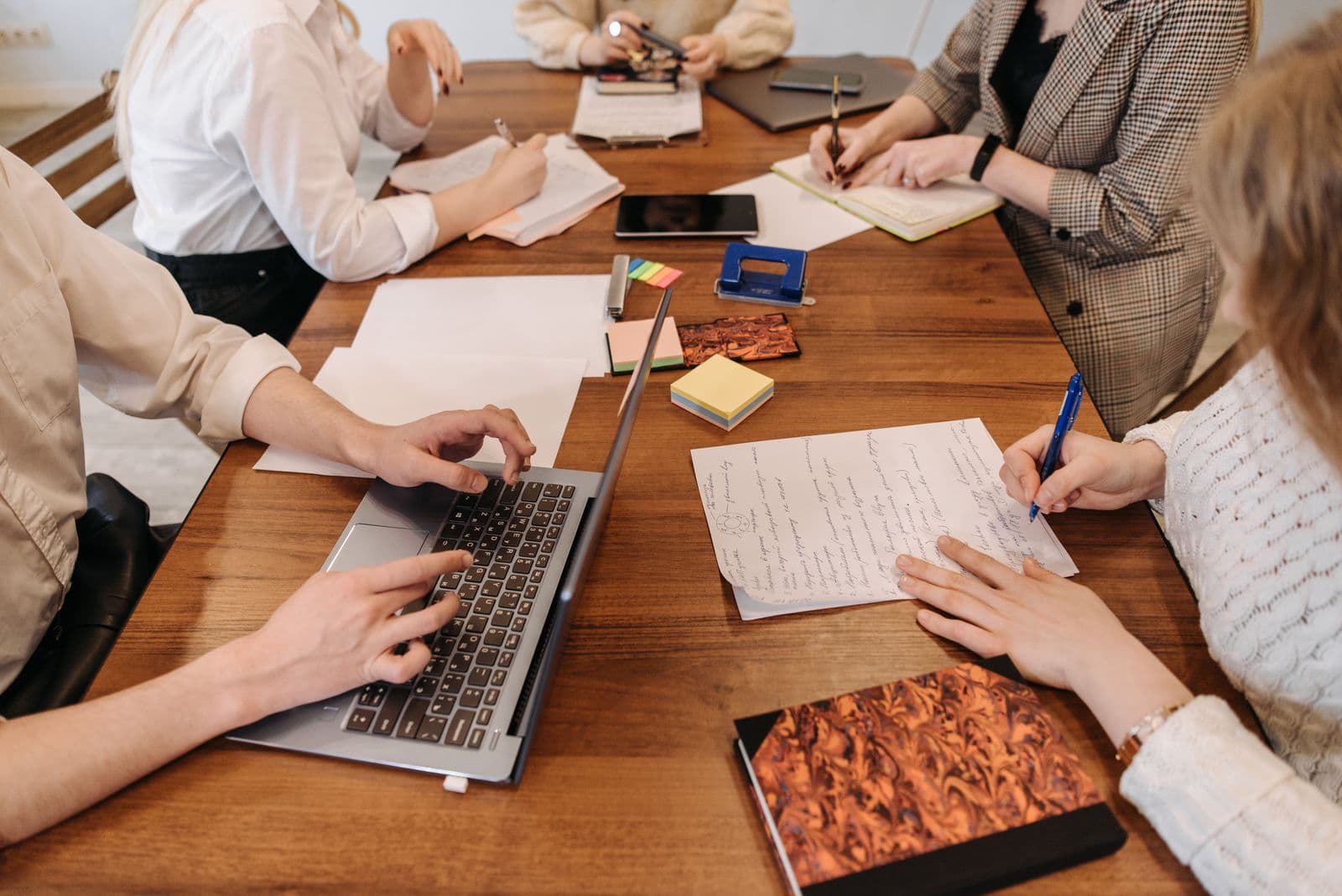 A person taking notes on a laptop during a work meeting