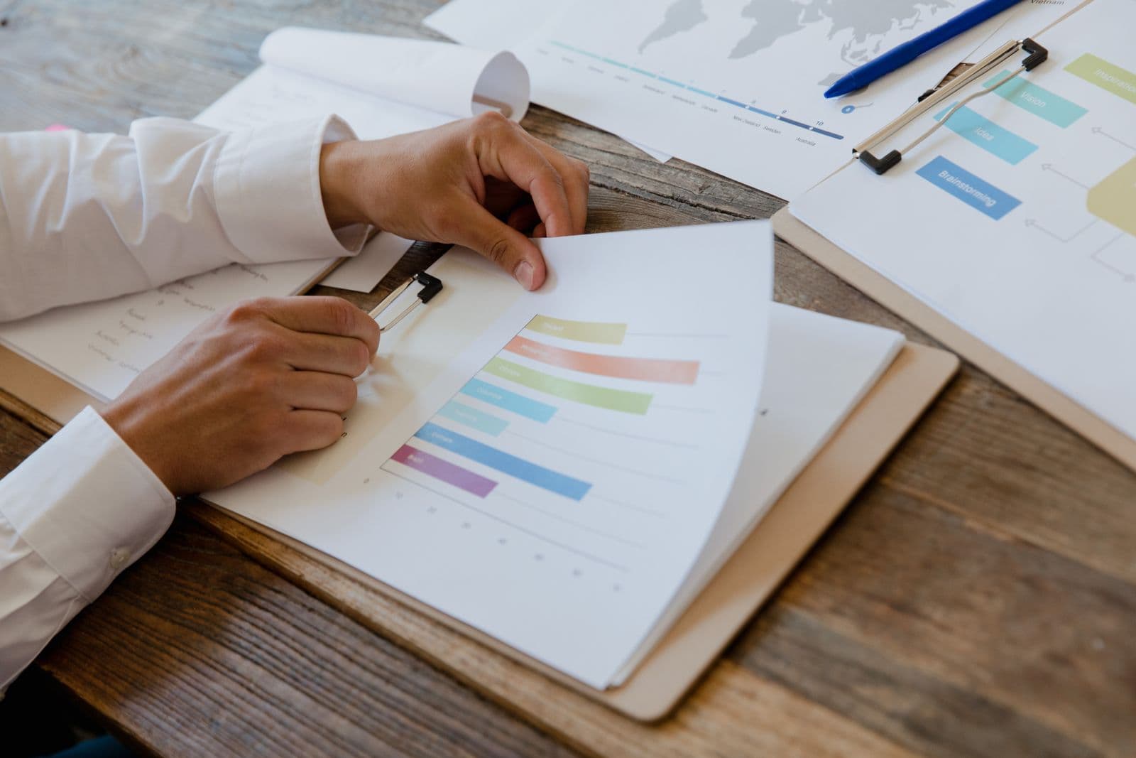 Printed business reports and performance charts spread across a desk