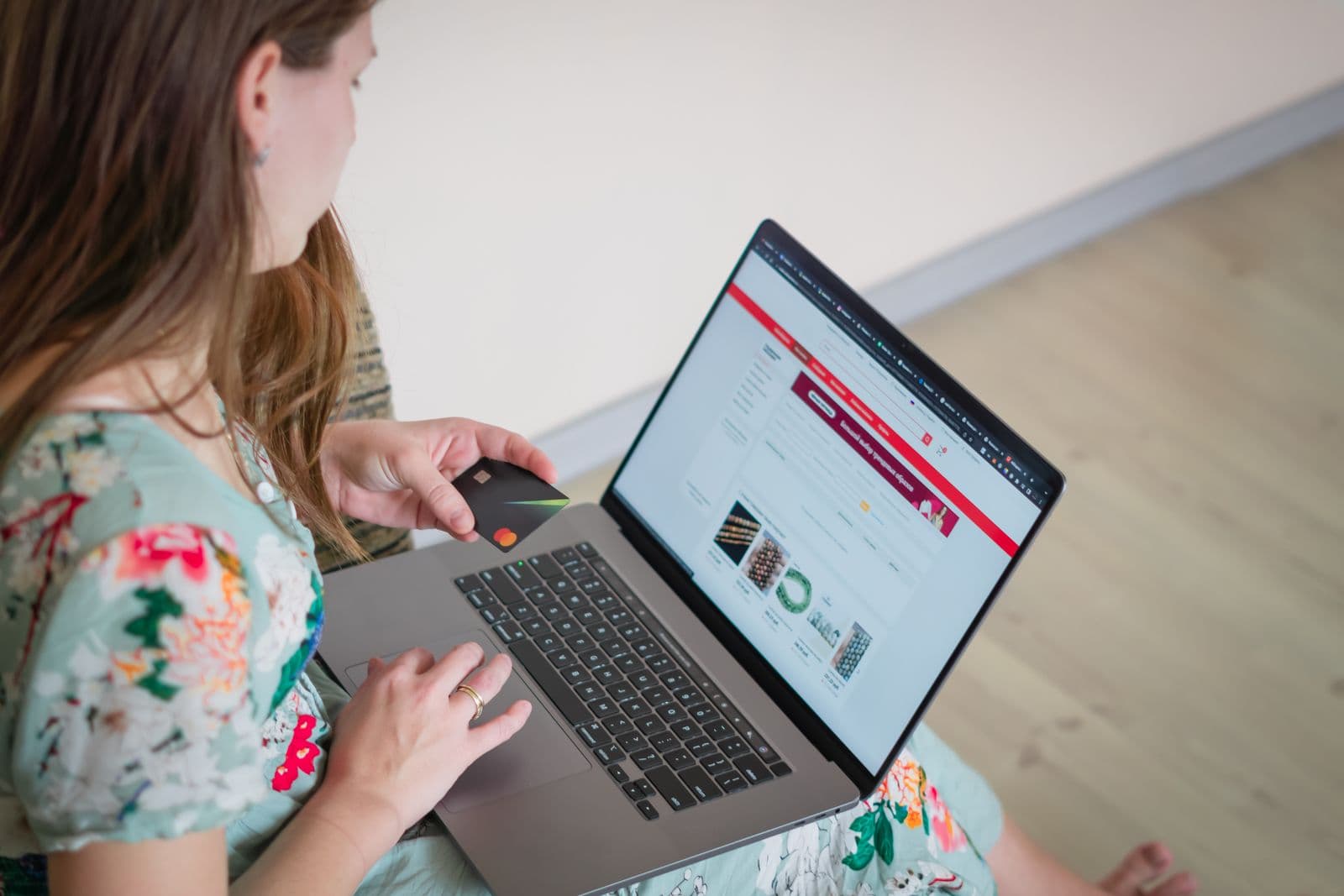 A person comparing products on a laptop with a credit card in hand during online checkout