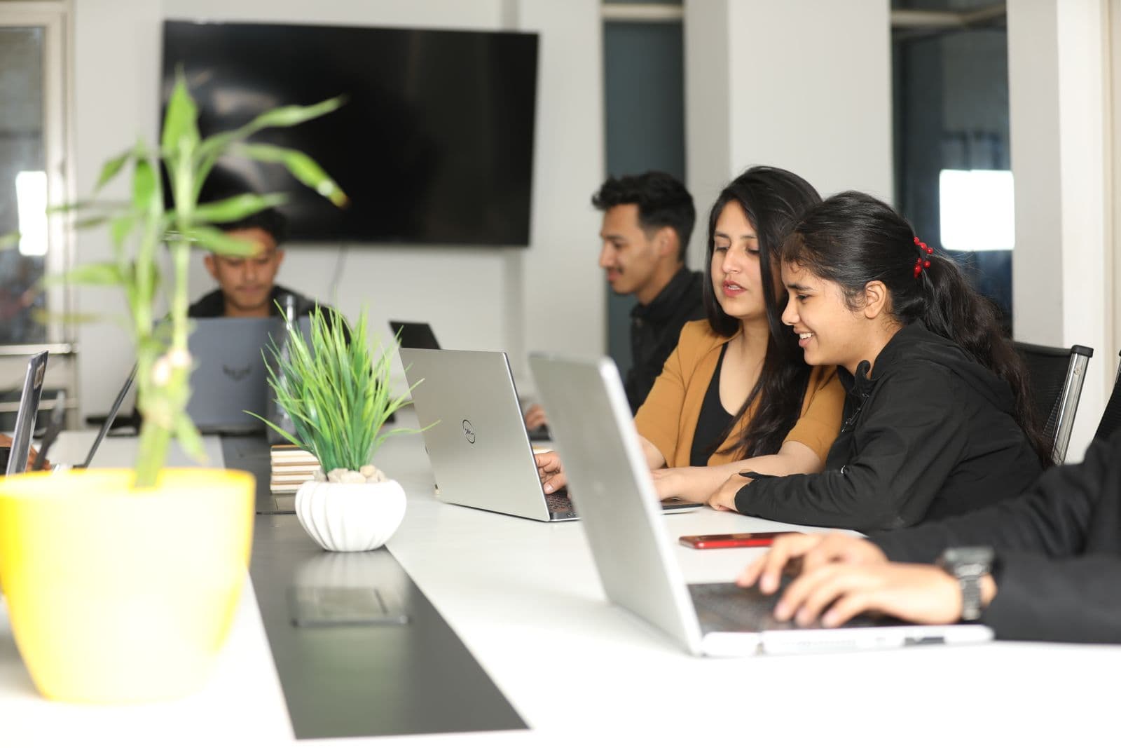 Four colleagues working at laptops along a long desk in a bright Kathmandu office