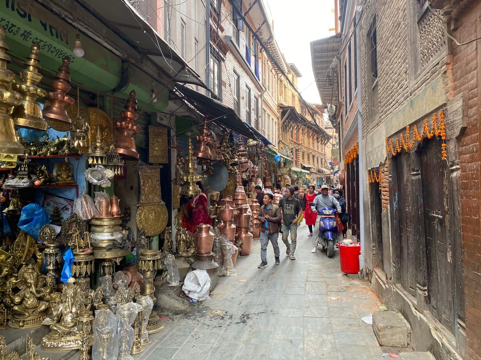 A small local business storefront on a busy street in Nepal with hand-painted signage